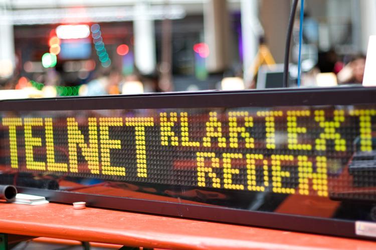 A flip-dot display, showing the text "Telnet: Klartext Reden"